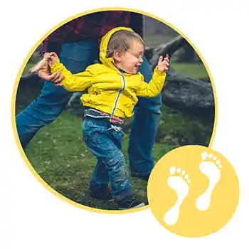 Child in a yellow raincoat holding hands with an adult outdoors, with a yellow footprint icon.