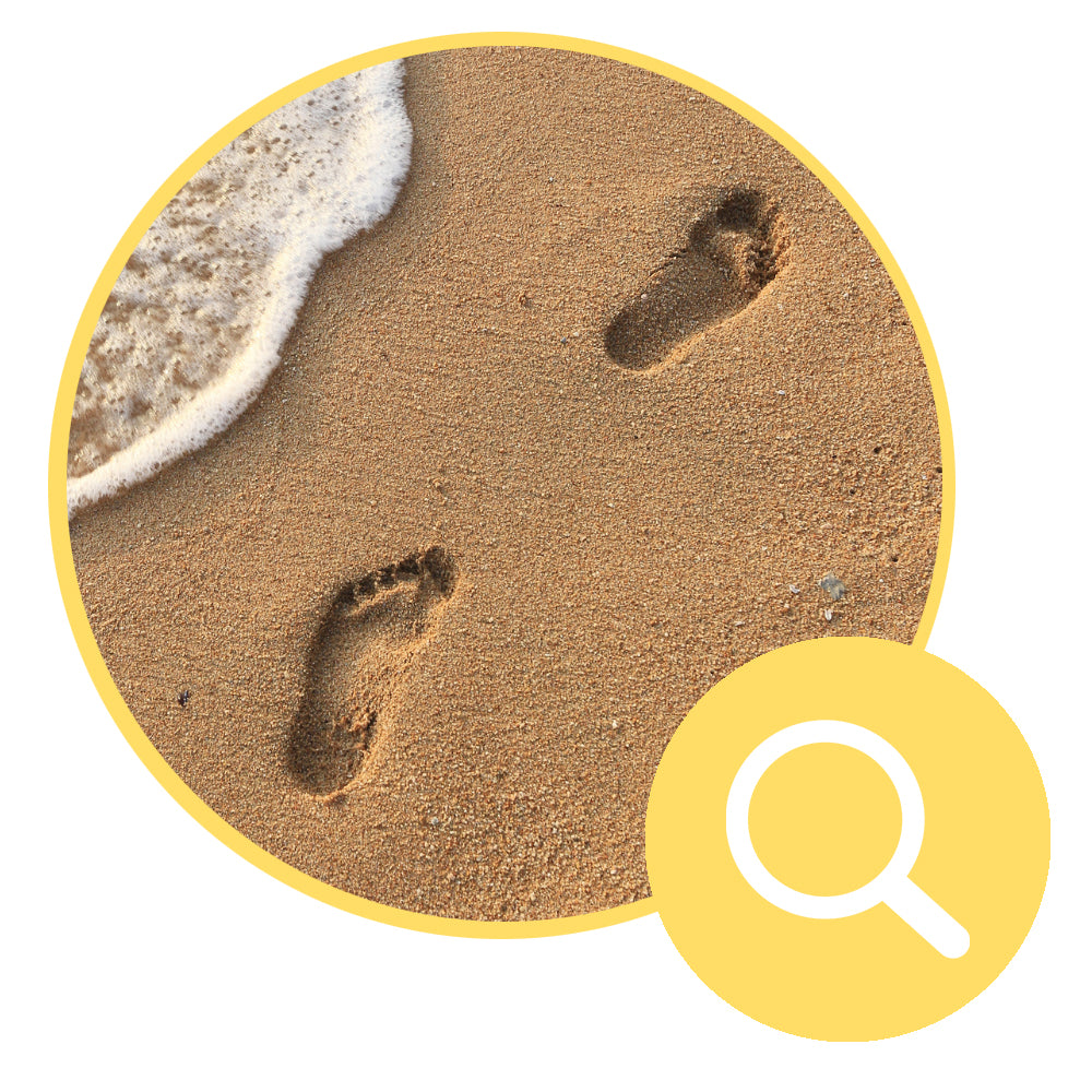 Footprints in sand with magnifying glass