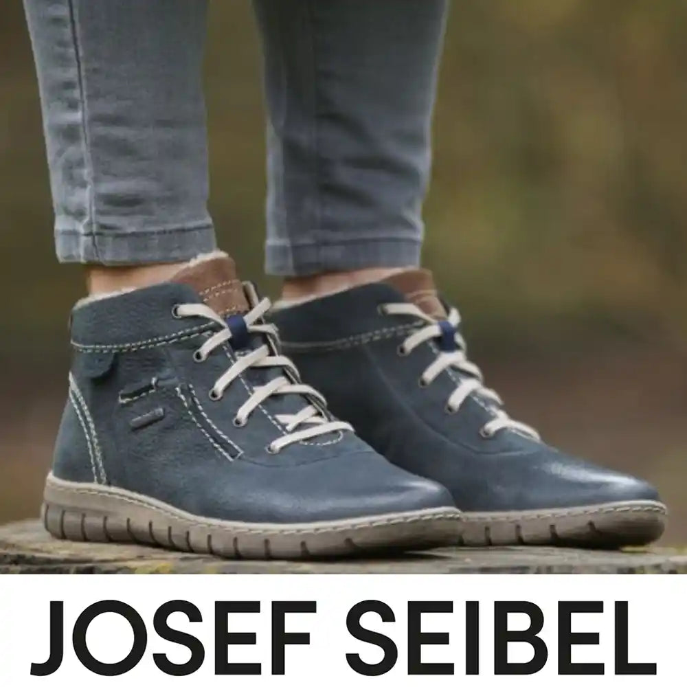 Blue shoes with white laces worn by a person, standing on a wooden block with 'Josef Seibel' branding.
