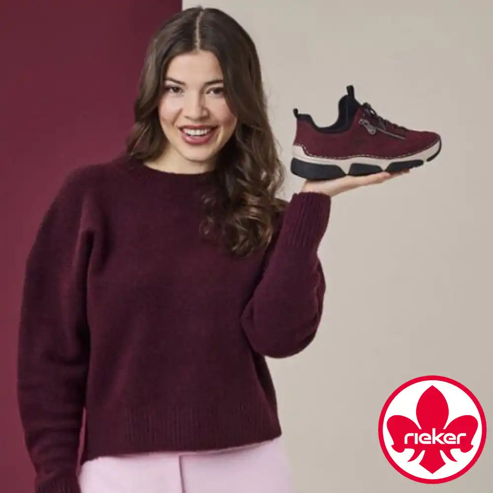 Woman holding a maroon sneaker against a plain background with a visible 'nike' logo.
